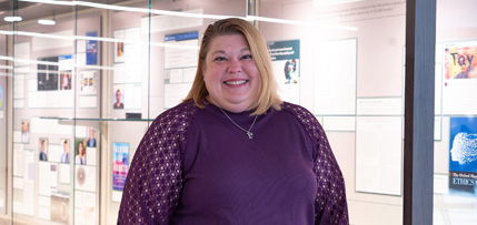 Image of exhibit curator, Danielle Kane, standing in front of exhibit case