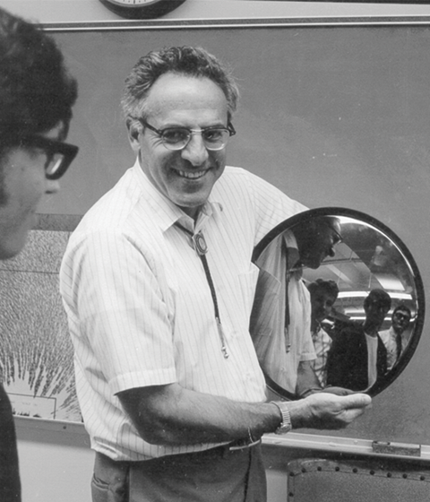 Frederick Reines holding a mirror of his guests